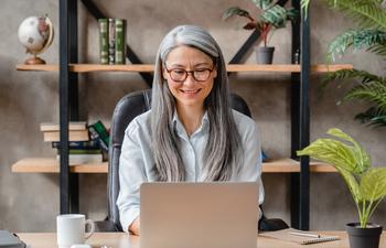 Love Your Job? Here's What Sticking With It for an Extra Year Could Do for Your Retirement: https://g.foolcdn.com/editorial/images/771317/older-woman-laptop-smiling-gettyimages-1304724400.jpg