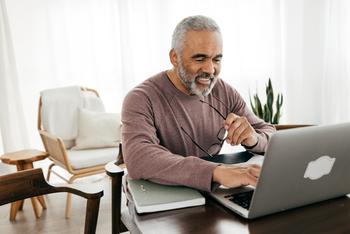 Answering These 2 Questions Can Tell You When You Should Sign Up for Social Security: https://g.foolcdn.com/editorial/images/778569/smiling-person-holding-glasses-and-looking-at-laptop.jpg