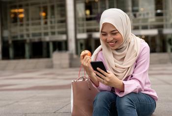 Buying Apple Stock Is a Smart Move, Only if This 1 Thing Happens: https://g.foolcdn.com/editorial/images/756779/woman-hijabi-eating-apple-on-phone-online-banking.jpg