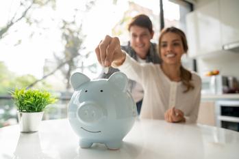 Are You Missing Out on These 2 Double-Digit Dividend Raises?: https://g.foolcdn.com/editorial/images/719436/couple-in-a-kitchen-placing-coins-into-a-piggy-bank.jpg