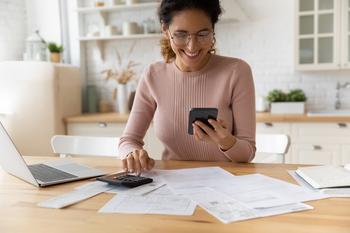 3 Things You Need to Know About the Student Loan Interest Deduction: https://g.foolcdn.com/editorial/images/735137/smiling-person-looking-at-smartphone-and-typing-on-calculator.jpg