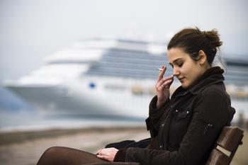 Why Carnival Stock Sank Today While Royal Caribbean Sailed Happily Along: https://g.foolcdn.com/editorial/images/703919/unhappy-person-smoking-while-seated-with-a-cruise-ship-in-the-background.jpg